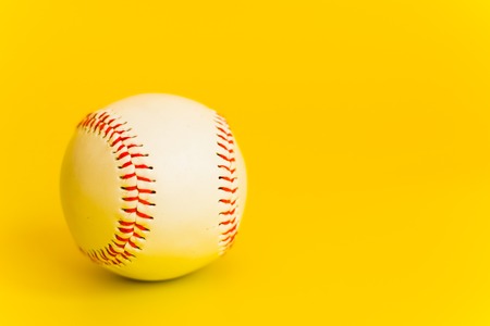 standard white baseball ball with seam red thread on yellow fonenの写真素材