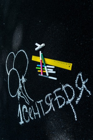 white chalk on black asphalt inscription in Russian September 1. yellow line, colorful markers,...