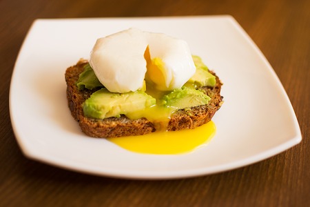 American breakfast. avocado sandwich and poached eggs on rye bread.の写真素材