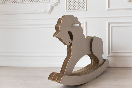 white cardboard horse, childrens toy swinging. interior white wall.の写真素材