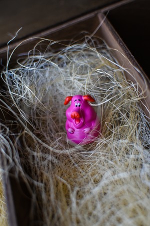 little toy pink figurine pig in straw in wooden box like a barn. symbol of year. new year 2019の写真素材