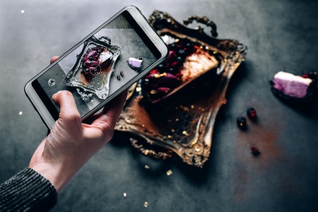 girl's hand shoots food dessert on the phone. chocolate souffle pudding cake filled with fresh berries on the Golden tray.の写真素材