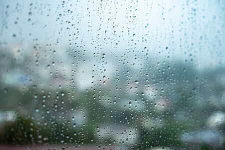 raindrops on the glass outside the window cloudy sky and greenery.の写真素材