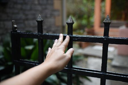 female hand opens the gate to a private yard. vintage fenceの写真素材