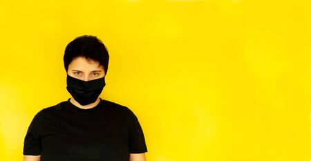 girl brunette short hair LGBT black mask serious look yellow background, banner. coronavirusの写真素材