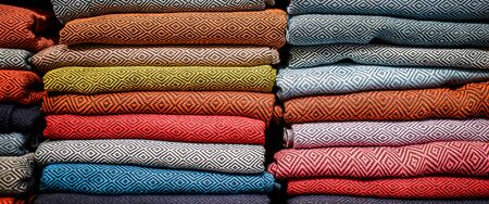 stacked multicolored clothing fabric in the closet bed linen banner.の写真素材