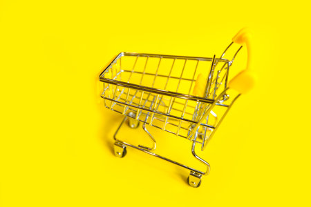 an empty shopping cart on a bright yellow backgroundの写真素材