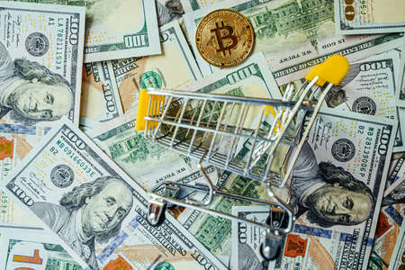 Bitcoin vs Dollars Shopping Cart Background of Hundreds of Dollars Green Yellowの写真素材