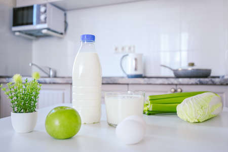 organic white dairy farm protein products on the kitchen table a bottle of milk and a cup. eggs green celery napa cabbage appleの写真素材
