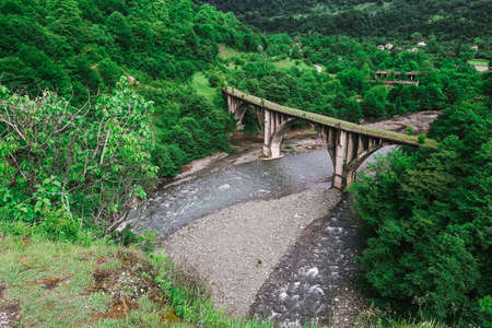 top view of an abandoned arch bridge in the mountains above the river. among the spring foliageの写真素材