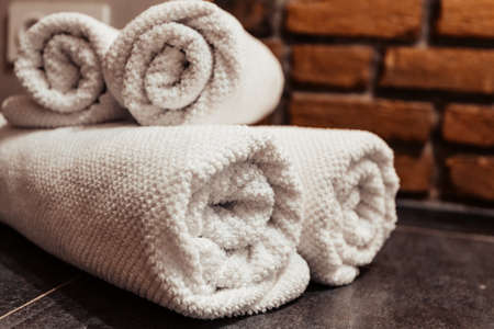 corner of the bathroom on a gray surface white towels are stacked in rolls loft style brick walls.の写真素材