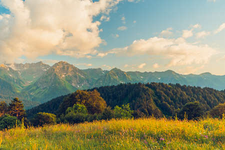 Landscape warm sunset in the mountains with sunlight shining orange clouds.の写真素材