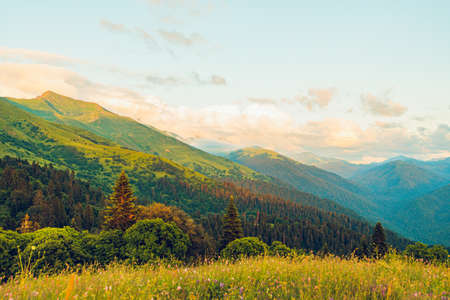 Landscape warm sunset in the mountains with sunlight shining orange clouds.の写真素材
