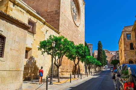 Pedestrians walking between old houses Spanish architecture apartment buildings on a tiny street in central barcelona with parked cars. Barcelona Spain 15 July 2017のeditorial素材
