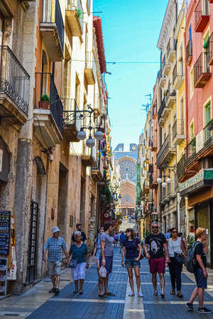 Pedestrians walking between old houses Spanish architecture apartment buildings on a tiny street in central barcelona with parked cars. Barcelona Spain 15 July 2017のeditorial素材