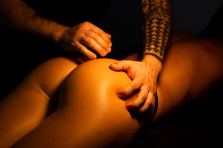 male hands sports buttock massage in a dark studio. Close-up view