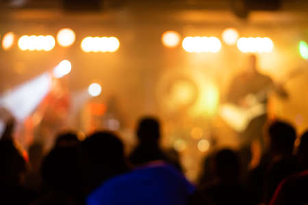 silhouettes of concert crowd in front of bright stage lightsの写真素材