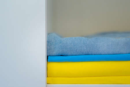 clothes of bright colors are neatly stacked. yellow blue colors of the Ukrainian flag in the closet.の写真素材