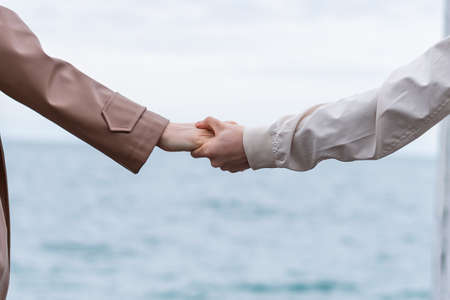 lovers holding hands on the background of the sea. the cold season. concept of vacation, rest.の写真素材
