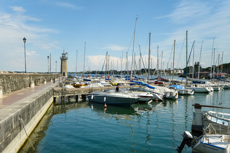 sailing boats and speedboats are moored in the port of Lake Garda Italyの写真素材