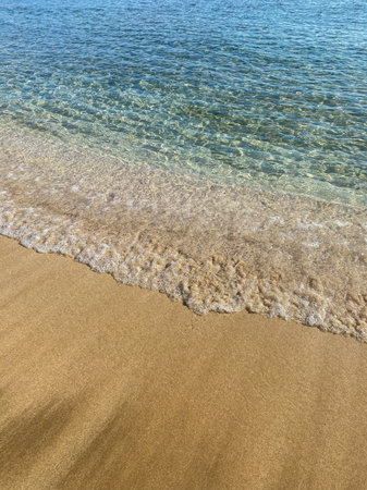 Bright turquoise sea wave on yellow sand. vertical photo