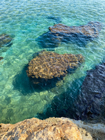 Top view of calm turquoise sea water and underwater rocks. Waves on rocks in the middle of the seaの写真素材