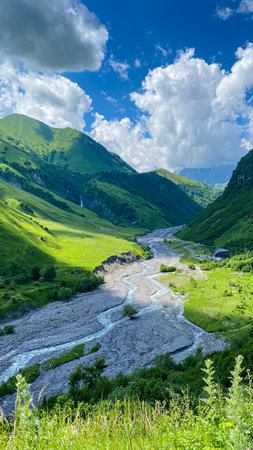 A colorful landscape with high Caucasus mountains, a beautiful winding river, green forest in summer...