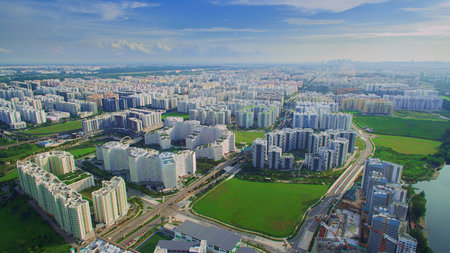 An aerial view of Punggol, Singapore, showcasing modern residential buildings, lush green spaces,...