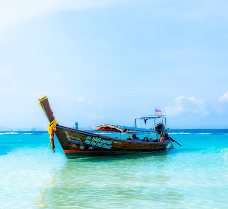 A traditional long-tail boat rests in the crystal-clear waters near Bamboo Island, Krabi, Thailand, adorned with colorful decorations under a clear blue sky.の写真素材