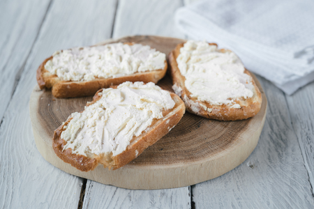 Wooden stand with homemade rustic sandwiches on a white wooden table. Sandwiches with white cream-cheese.の写真素材