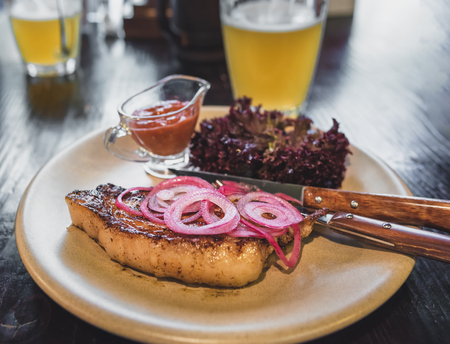 Steak with red onion, sauce, lettuce and beer served in a restaurantの写真素材