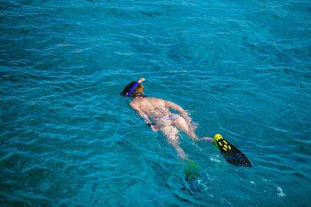 Young woman in a snorkeling mask and flippers swims in a clear turquoise water of a sea. Snorkeling...