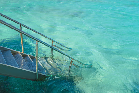 Metal staircase to the clear turquoise water of a sea for swimming. Summer vacation at exotic resortの写真素材