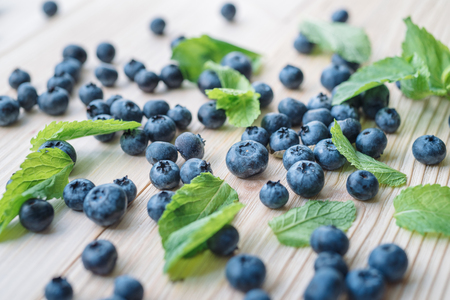 Macro photo of blueberries on a wooden table. Mint leaves with blackberries. Healthy breakfast with vital vitamins.の写真素材