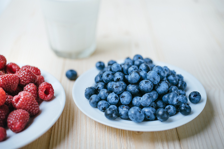 Rustic healthy breakfast with blueberry, raspberry and milk in a glass on a white wooden table. Healthy breakfast with vital vitamins.の写真素材