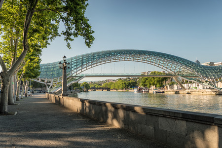 The Bridge of Peace in Tbilisi. View at the futuristic bridge made of glass and metal over a Mtkvari river in the center of old Tbilisi.の写真素材