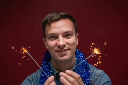 Excited man in a blue jeans shirt holding Bengal lights celebrating Christmas and New Year. Having a...