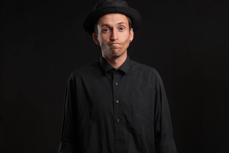Stylish handsome man a black shirt and pork pie hat isolated over black background. Low key portrait.の写真素材