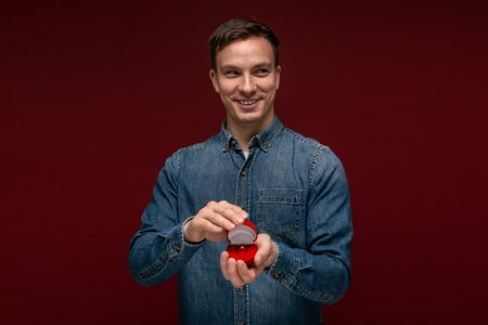 Young man making wedding proposal holding box with engagement ring. Concept of love