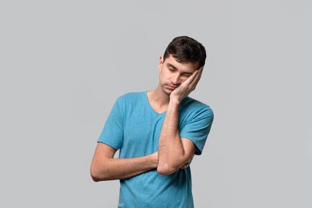 Young brunet man sleeping isolated over grey background. Being tired after long working day. Concept of sleeping.の写真素材
