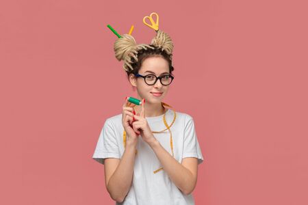 Smiling teenager in a white shirt and glasses and measuring tape on a neck and scissors in dreads. Being creativeの写真素材
