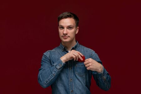 Young man hiding box with engagement ring into the pocket of a shirt. Concept of wedding proposal