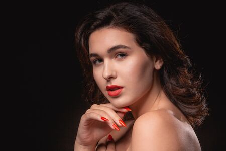 Beautiful woman with bright makeup posing isolated over black background. Image of young beautiful woman with red lipsの写真素材