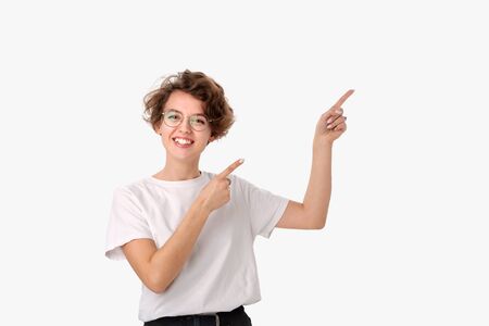 Pretty smiling woman in white shirt and eyeglasses pointing at copy space. Place for advertisingの写真素材
