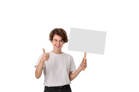 Smiling young woman holding empty signboard with copy space and showing thumb up. Concept of positive social awareness.の写真素材