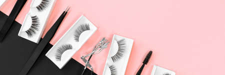 Various tools for eye lash extensions on trendy pastel pink and black background. Banner. Makeup. Fake eyelashes.の写真素材