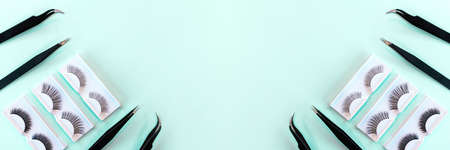 Different tools for eye lash extension on trendy pastel mint blue background. Fake eyelashes and tweezers. Beauty concept. Makeup cosmetics. Top view, flat lay. Layout. Place for text. Banner.の写真素材