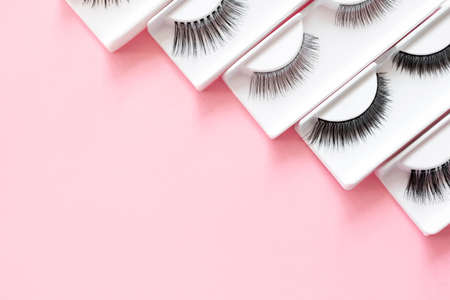 Different false eyelashes on a trendy pastel pink background. Beauty pattern. Makeup accessories. Cosmetics products for women. Top view, flat lay. Place for text. Layout. Copy space.の写真素材
