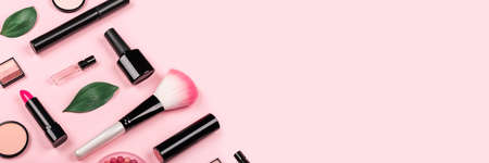 Various cosmetic accessories for makeup and manicure on trendy pastel pink background. Blush, brush, eye shadow, mascara, perfume, lipstick, nail Polish. Skin care products. Copy space. Banner.の写真素材