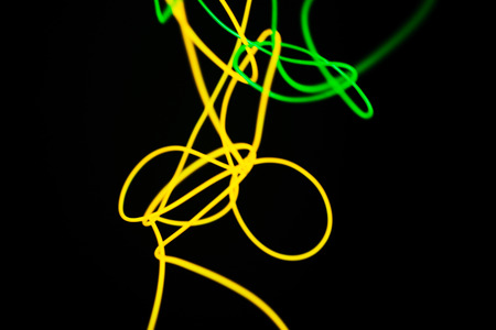 Yellow neon and green neon abstract. Neon lines. Isolated on black background.の写真素材